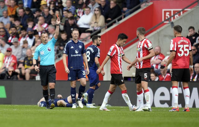 Stuart Attwell raises a red card above his head as he sends off Southampton’s Jack Stephen against Manchester United, with Alejandro Garnacho on his back behind the referee after being fouled. 