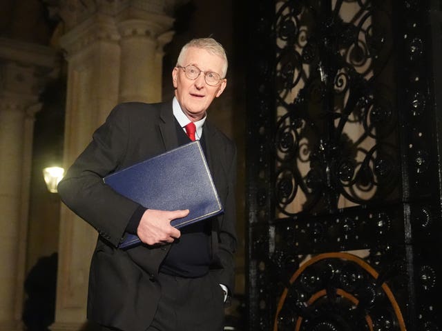 Hilary Benn walking down steps holding a blue folder