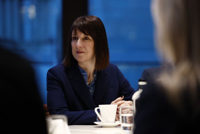 Chancellor Rachel Reeves sat at a desk with a white mug in front of her listening to top executives in central London