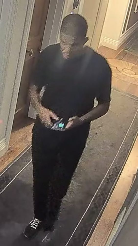 CCTV image of Mussie Imnetu in a dark t-shirt. He is looking downwards at his phone in his hands