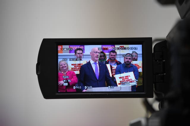 First Minister John Swinney is seen in the view screen of a TV camera as he delivers a speech in Glasgow