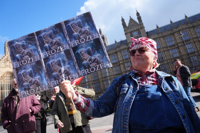 A protester carrying a sign saying "Frozen" protests against the decision to means test the winter fuel payment