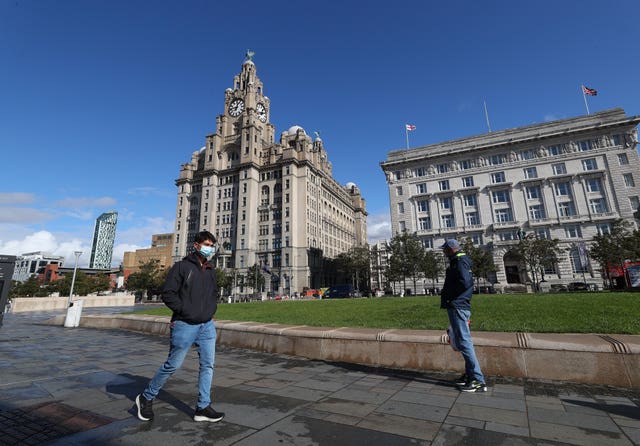 A man in a face mask walks past the Liver Building in Liverpool
