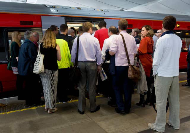 Commuters waiting to board a train (Yui Mok/PA)