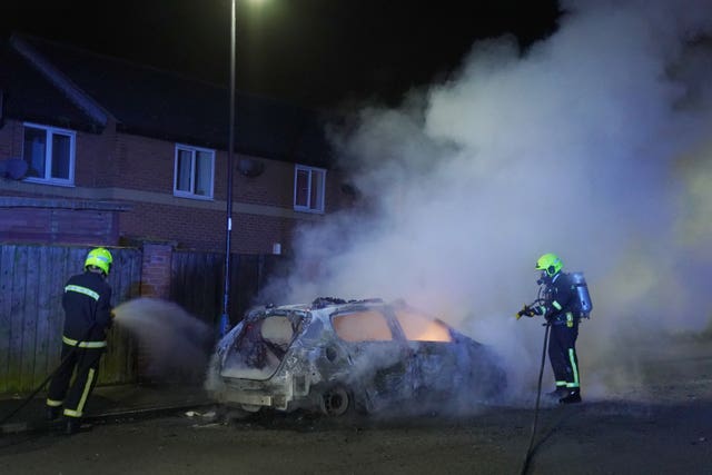 Firefighters tend to a burning police car burns as officers are deployed on the streets of Hartlepool following a violent protest.