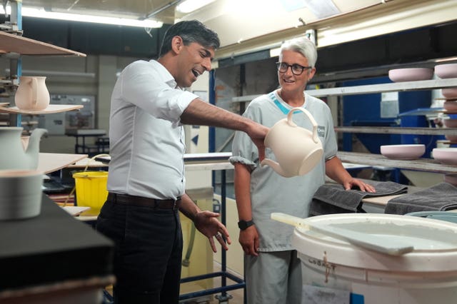 Prime Minister Rishi Sunak dipping pots with staff member Georgia Plinston during his visit to Denby Pottery Factory, Ripley