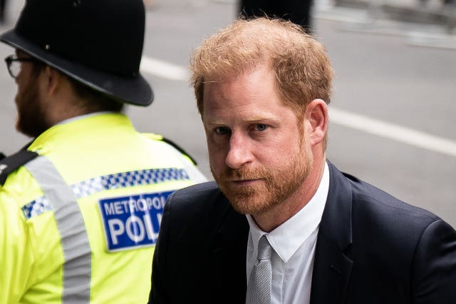 Harry walking into the High Court, past a uniformed police office, at the MGN phone hacking trial 