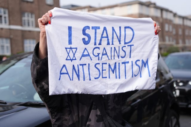 A member of the public holds a sign against antisemitism 