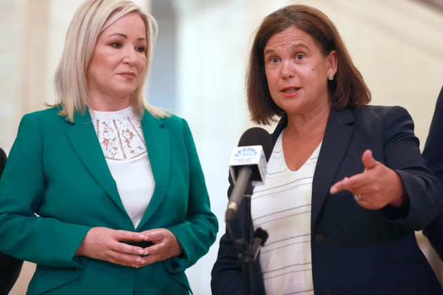 Mary Lou McDonald, right, gestures and talks into a microphone while Michelle O'Neill stands alongside her with her hands clasped in front of her