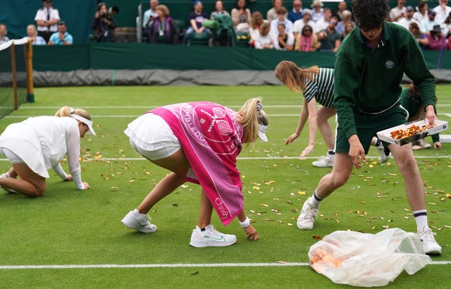 Katie Boulter helps ground staff clear confetti from Court 18 