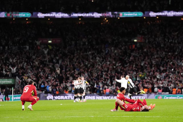 Liverpool’s Curtis Jones squats down and Darwin Nunez lies on the pitch as Newcastle players celebrate in the background