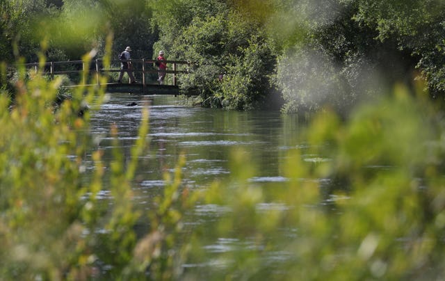 People walk across a bridge over the river Itchen near to Ovington in Hampshire (Andrew Matthews/PA)