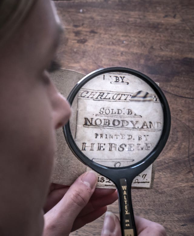 Curator Sarah Laycock uses a magnifying glass to inspect the last Charlotte Bronte miniature manuscript book known to be in private hands, as the book goes on display following its return to the Bronte Parsonage Museum in Haworth, Keighley, West Yorkshire, once the home of the Bronte family 