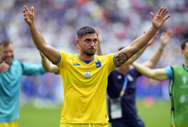 Ukraine’s Roman Yaremchuk raises both arms in the air 