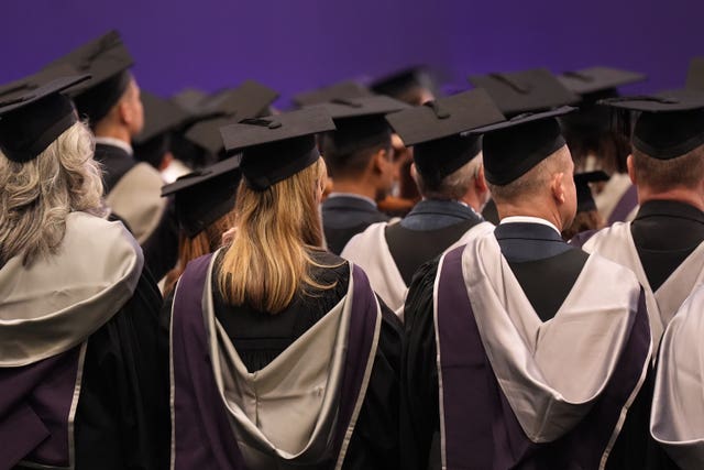 The backs of university graduates wearing their robes and caps