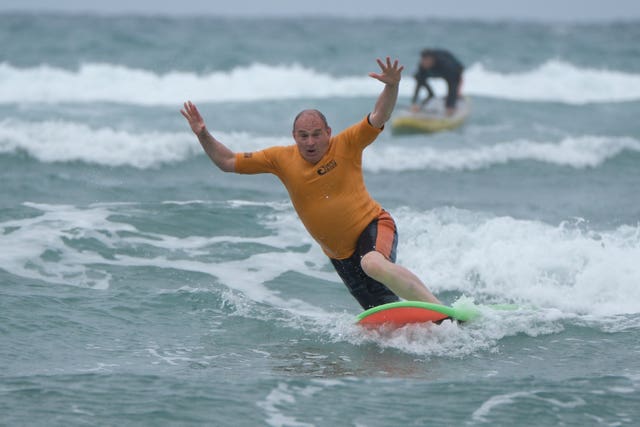Sir Ed Davey tries to stand up on a surf board - but doesn't quite make it