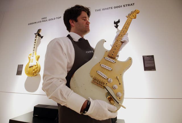 An art handler cradles the 1954 white Fender Stratocaster