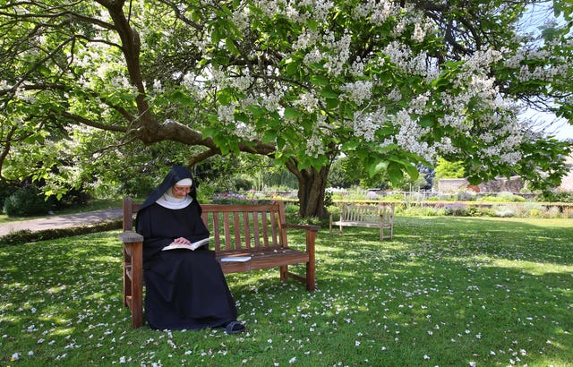 Mother Mary David reads in the gardens 