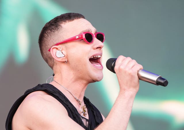 Olly Alexander, wearing red-rimmed sunglasses, singing into a microphone on stage at the BBC Radio 1 Big Weekend in Luton