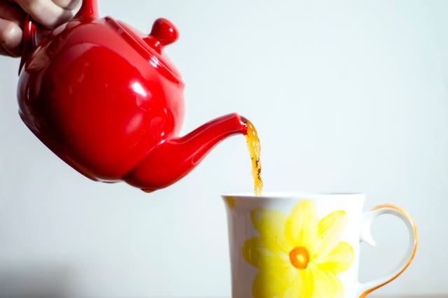 Teapot pouring tea into mug