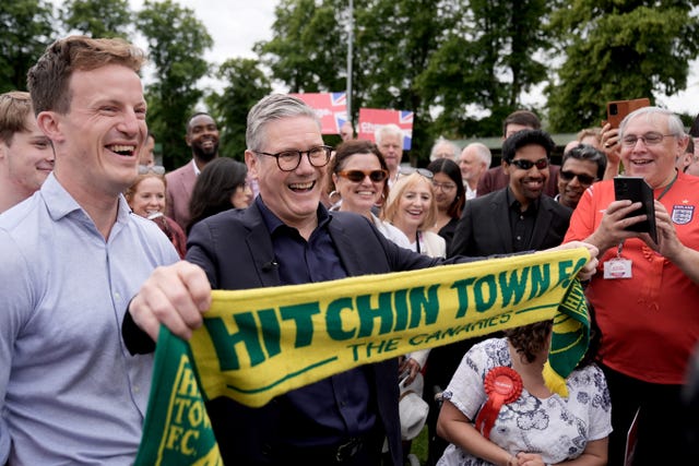 Sir Keir Starmer holds up a scarf