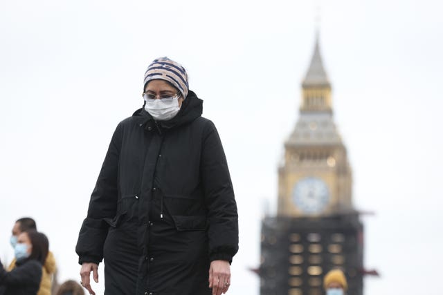 A woman wearing a face covering walks over Westminster Bridge, central London