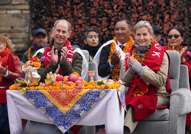 The Duke and Duchess of Edinburgh clap while sat at a table