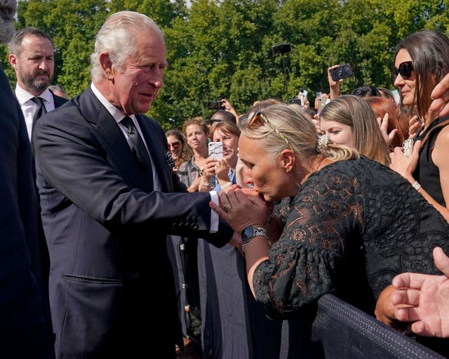 A well-wisher kisses the hand of King Charles III during a walkabout outside Buckingham Palace
