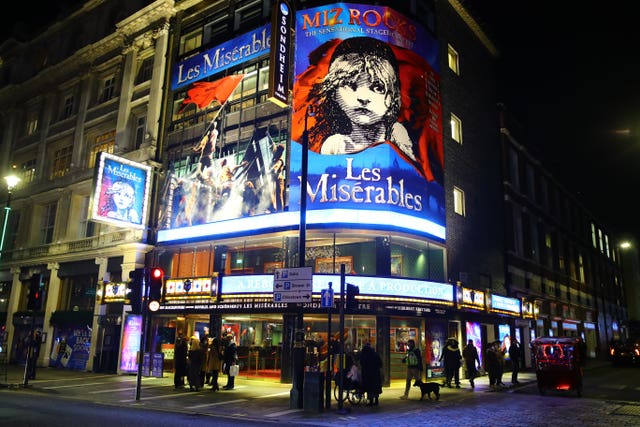 External view of the Sondheim Theatre, with a sign lit up showcasing Les Miserables