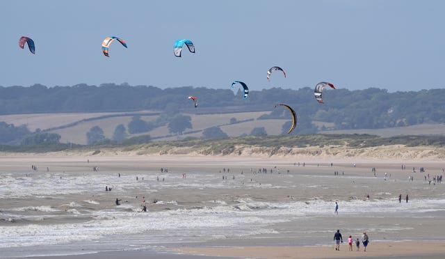 Kite surfers enjoy the windy conditions on the sea at Camber Sands in East Sussex on Sunday 