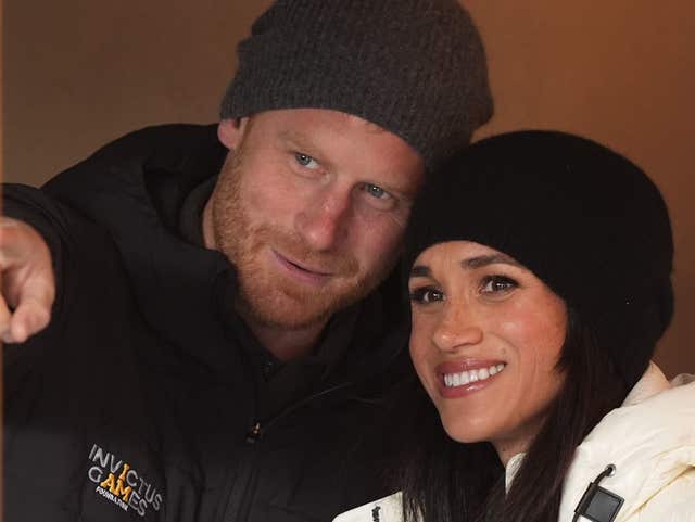 The Duke and Duchess of Sussex wearing matching winter hats chat with their heads close together as they attend the Whistler Welcome Celebration at the 2025 Invictus Games in Whistler, Canada in February