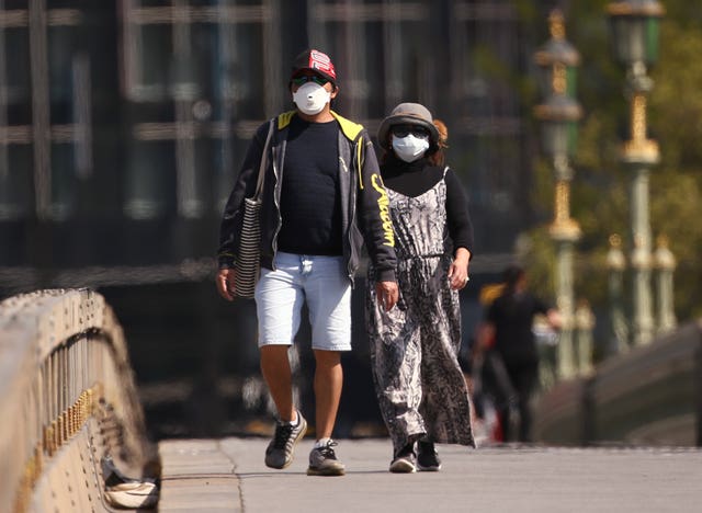 A couple wearing face masks on Westminster Bridge, London (Yui Mok/PA)