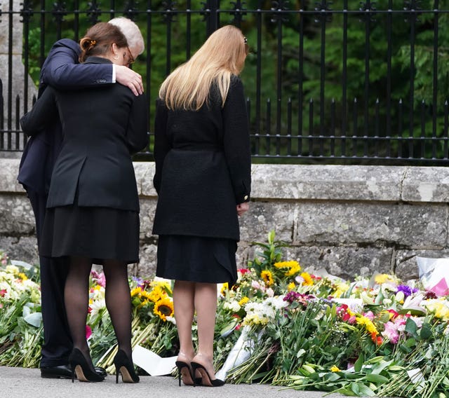 The Duke of York with his arm around Princess Eugenie as they view tributes with Princess Beatrice