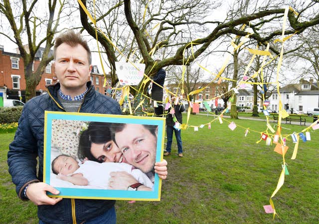 Richard Ratcliffe holds a photograph of himself with wife Nazanin and daughter Gabriella (John Stillwell/PA)