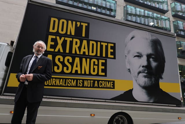 John Shipton, father of WikiLeaks founder Julian Assange, stands in front of a support poster as he arrives at the Old Bailey