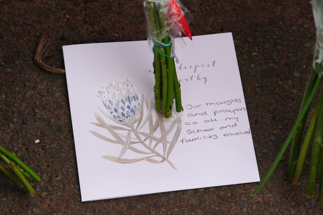 A note left on a bunch of flowers among the floral tributes at the entrance to Minehead Middle School in Somerset