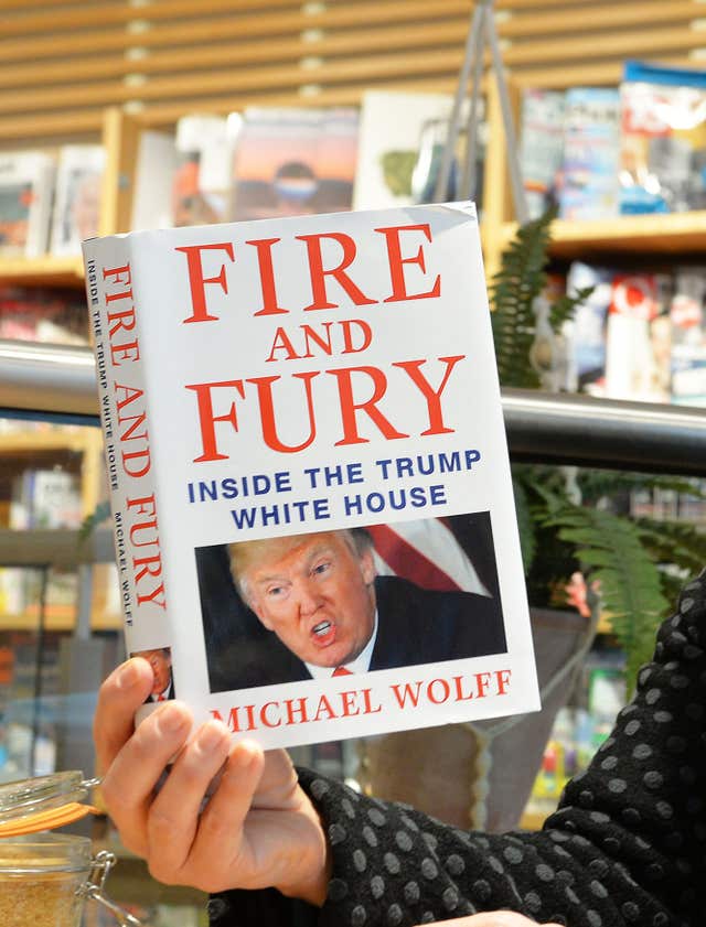 Woman holds Fire And Fury book  (John Stillwell/PA)
