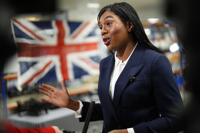 Kemi Badenoch gesturing while speaking to the media with a Union flag in the background