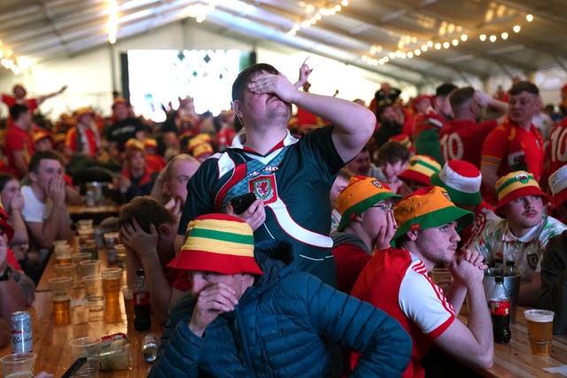 Wales supporters at the fan park in Swansea look dejected at the prospect of elmination (Jacob King/PA)