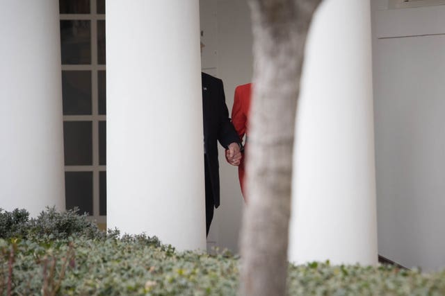 Theresa May and Donald Trump hold hands as they walk along the White House Colonnade