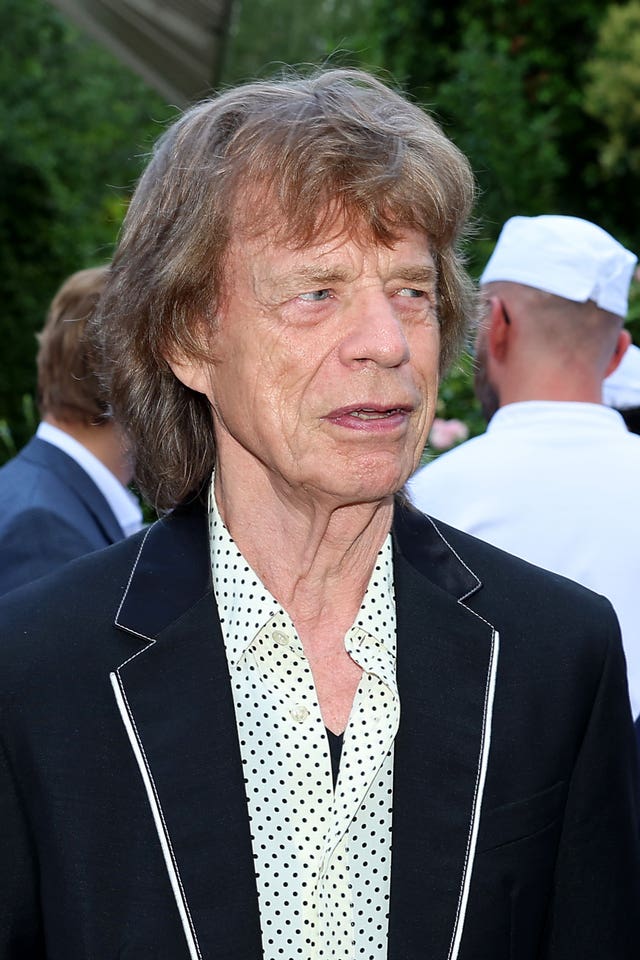 Sir Mick Jagger in black jacket and polka dot shirt