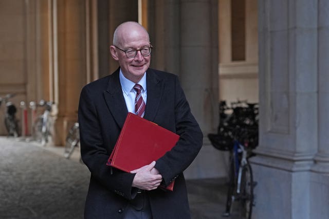 Pat McFadden smiling while carrying his red ministerial folder