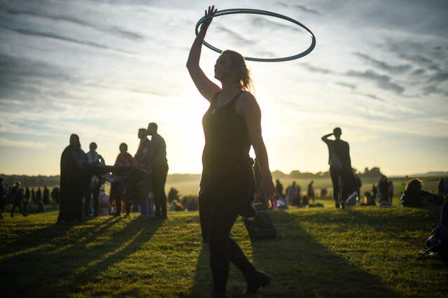 A woman twirls a hula-hoop as the sun rises at Stonehenge (Ben Birchall/PA)