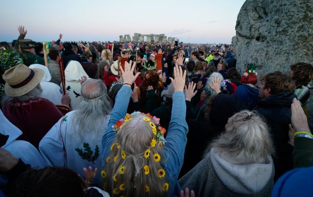 People gather around the Heel Stone ahead of sunrise as they take part in the summer solstice at Stonehenge in Wiltshire