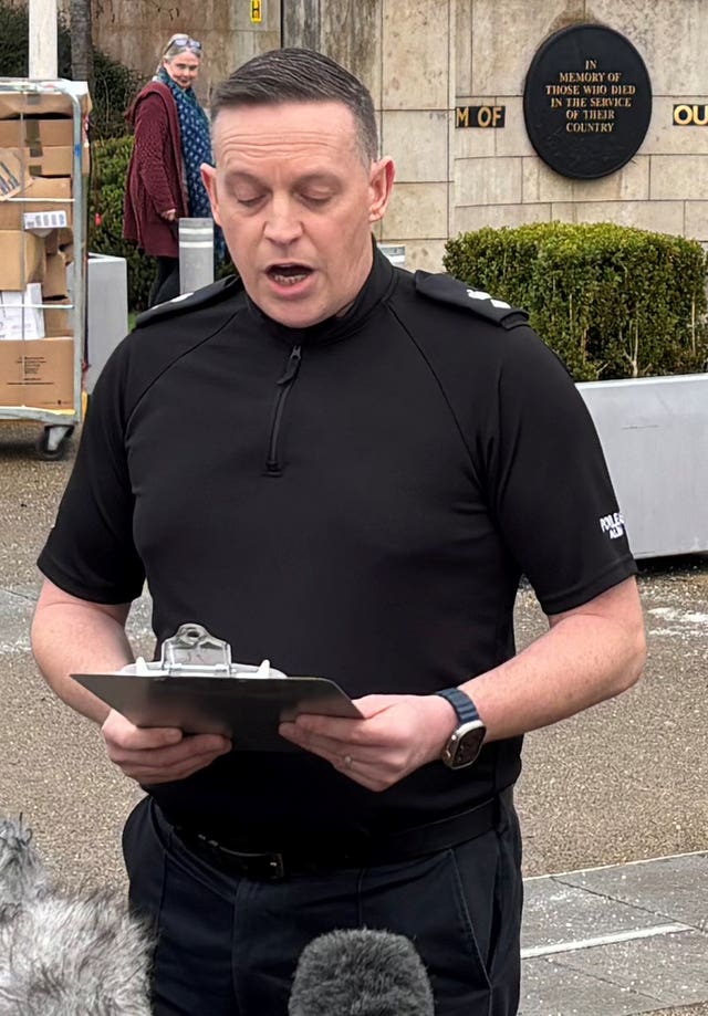 Police officers speaking outside a police station in front of microphones