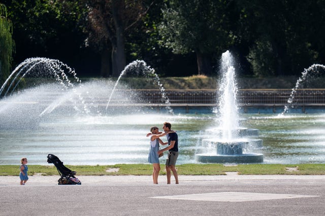 Two people embrace in front of a fountain