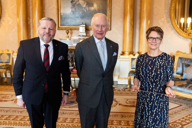 The King stands between Usher of the Black Rod of the Senate of Canada Gregory Peters and Senate Speaker Raymonde Gagne