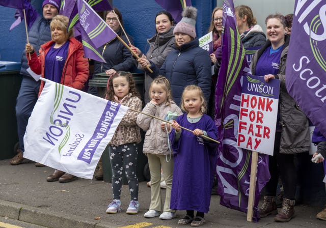 Children and adults on picket line, holding Unison flags