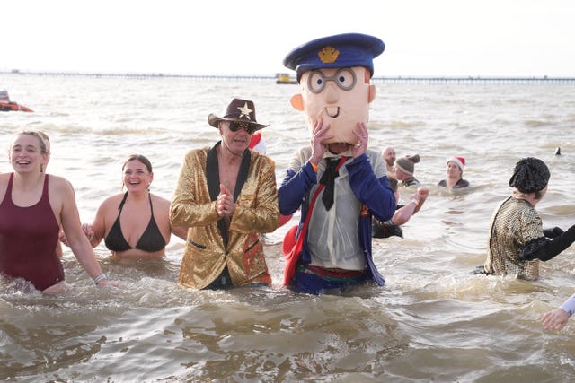 A man dressed as Postman Pat takes part in the Southend RNLI New Year Day Dip in Southend-on-Sea, Essex