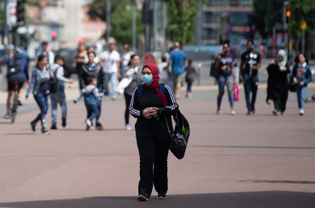 A woman wearing a protective face mask walks through the city centre of Leicester (Joe Giddens/PA)